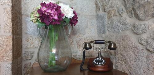 un vaso di vetro con fiori su un tavolo accanto a un telefono di Casa Do Conde a Caldas de Reis