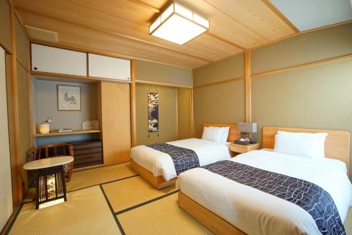 a hotel room with two beds and a table at Sakura Riverview Gion in Kyoto