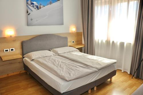 a bed in a bedroom with a large window at Appartamenti Forhotel in Livigno
