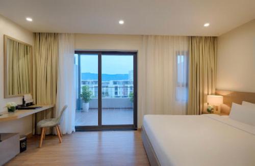 a bedroom with a large bed and a desk and a window at Royal Lotus Hạ Long Resort & Villas in Ha Long