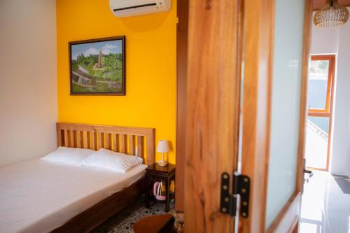 1 dormitorio con cama y pared amarilla en Trú Homestay Huế, en Thôn Dương Xuân Hạ