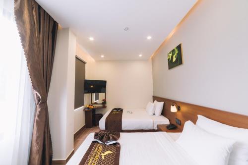 a hotel room with two beds and a television at GREENECO DA LAT HOTEL - Khách sạn Green Eco Đà Lạt in Da Lat