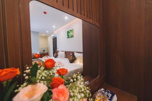 a bedroom with a bed and flowers in front of a mirror at GREENECO DA LAT HOTEL - Khách sạn Green Eco Đà Lạt in Da Lat