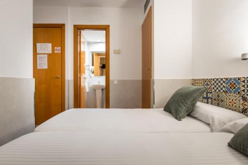 a bedroom with a large white bed and a bathroom at Hostal Baler in Barcelona