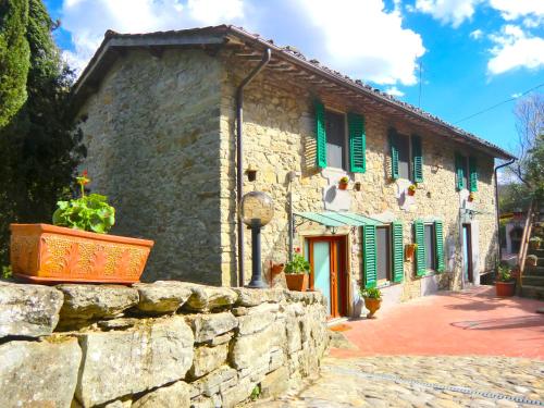 a stone house with green shutters and a stone wall at Ex-mulino Pontevecchio (mill on the river) in Pelago