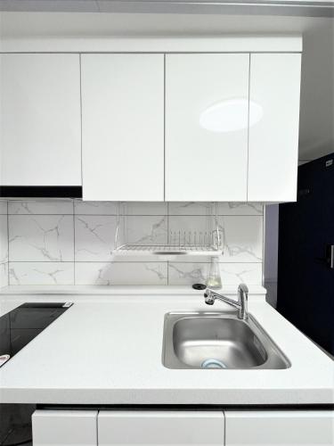 a kitchen with white cabinets and a sink at W Guesthouse Incheon airport in Incheon
