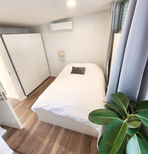Un pequeño dormitorio con una cama blanca y una planta en Assuta Residence in Ramat HaHayal, Tel Aviv en Tel Aviv