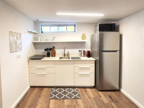 a kitchen with white cabinets and a stainless steel refrigerator at Assuta Residence in Ramat HaHayal, Tel Aviv in Tel Aviv