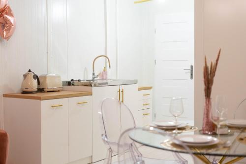 a white kitchen with a glass table and chairs at Ironland Roztocze in Ruda Żelazna