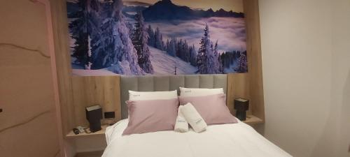 a bed with two pillows and a painting on the wall at DVOSJED apartmani Jahorina in Jahorina