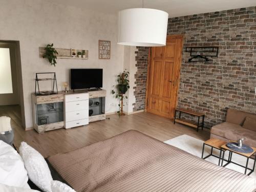 a living room with a television and a brick wall at Ferienwohnung Luise in Naumburg