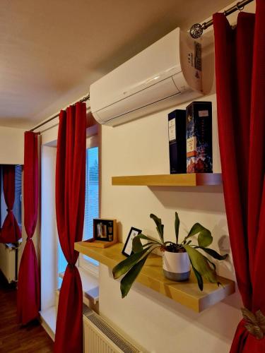 a room with red curtains and a plant on a shelf at Slnečný byt v blízkosti historického centra Free Parking in Trenčín
