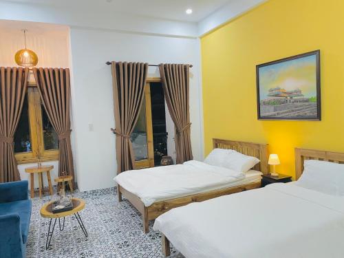 two beds in a room with yellow walls and windows at Trú Homestay Huế in Thôn Dương Xuân Hạ