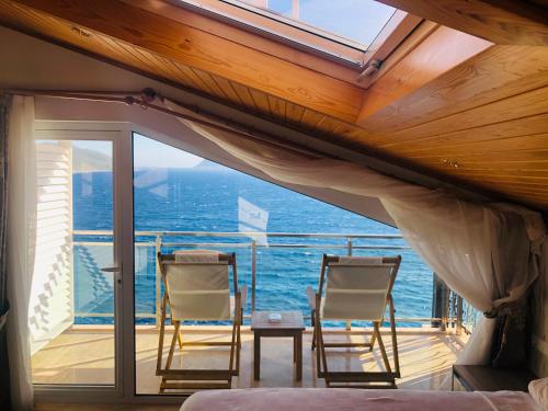 a bedroom with two chairs and a balcony with the ocean at Narr Hotel in Kaş