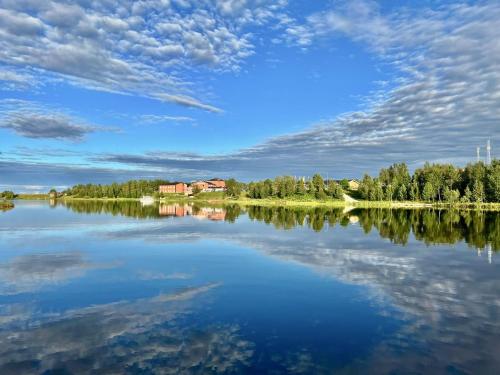 uma vista para um lago com uma casa à distância em Log Cabin - Lord of Sormuset em Inari