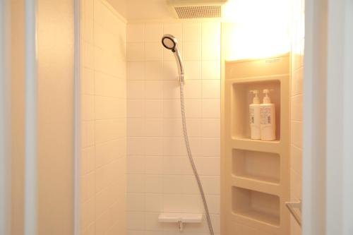 y baño con ducha con cabezal de ducha. en ゲストハウス昴 en Tokio