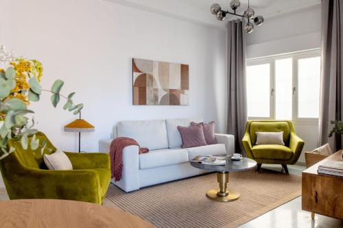 - un salon avec un canapé et deux chaises dans l'établissement Suites Maestranza - Puerta del Arenal by Magno Apartments, à Séville