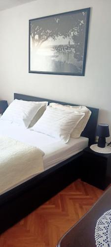 a bed with white sheets and pillows in a bedroom at Rab-centar in Rab