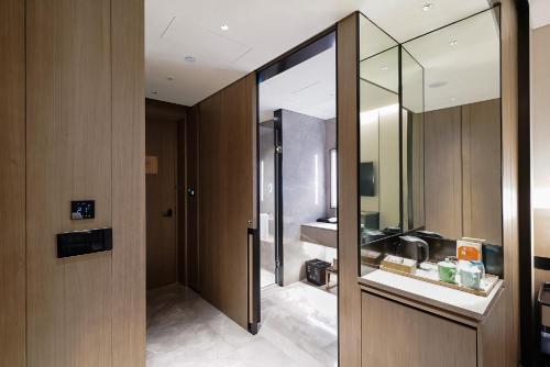baño con puerta de cristal y lavamanos en Genpla Hotel, Shenzhen Qianhai en Shenzhen
