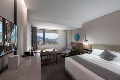 ein Hotelzimmer mit einem großen Bett und einem Schreibtisch in der Unterkunft Genpla Hotel, Shenzhen Qianhai in Shenzhen