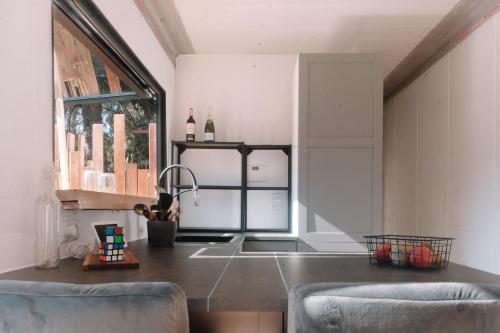 カステルデフェルスにあるCoolTainer retreat: Sustainable Coastal forest Tiny house near Barcelonaのキッチン(ステンレス製のカウンタートップ、椅子2脚付)