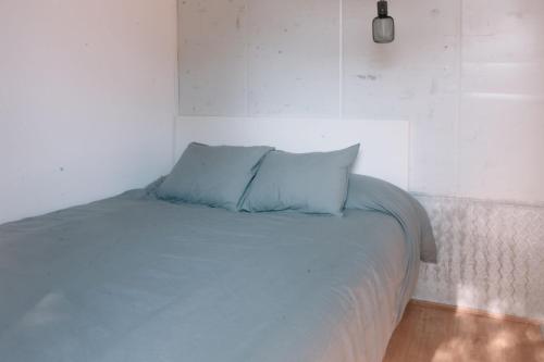 a bed with two blue pillows on top of it at CoolTainer retreat: Sustainable Coastal forest Tiny house near Barcelona in Castelldefels