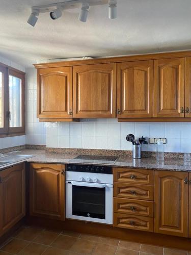 a kitchen with wooden cabinets and a stove top oven at Cal Bisbe in Segura
