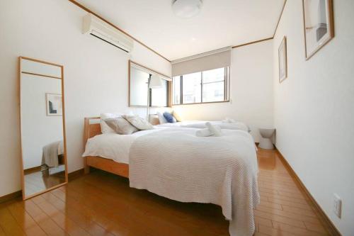 a bedroom with a bed with white sheets and a mirror at Pirane House 201 東京スカイツリー浅草 押上駅が徒歩圏内 無料wifi in Tokyo