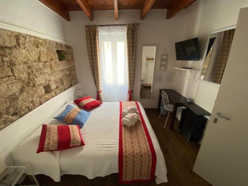 Schlafzimmer mit einem Bett mit roten und blauen Kissen in der Unterkunft Lu Bàtil B&B - Rooms in Alghero