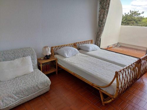 2 camas en una habitación con sofá y ventana en Appartement Le Grau-du-Roi, 2 pièces, 6 personnes - FR-1-716-1, en Le Grau-du-Roi
