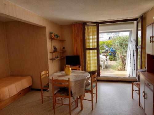 une salle à manger avec une table et une chambre avec une fenêtre dans l'établissement Studio double cabine RDJ avec loggia et jardinet, parking privé, 5 pers - La Grande-Motte - FR-1-716-26, à La Grande Motte
