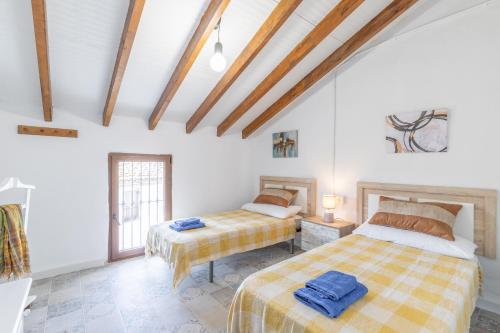 two beds in a room with white walls and wooden beams at La Cambra de la Clau in Polop