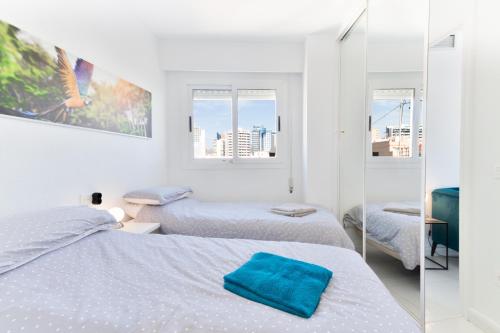 een witte slaapkamer met 2 bedden en een spiegel bij Old City Penthouse with fantastic views & parking in Benidorm