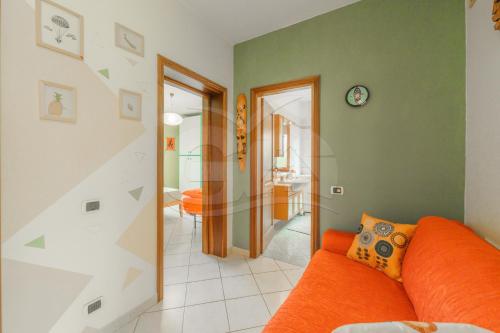 a living room with an orange couch and a hallway at A Casa di Zaira - Goelba in Portoferraio