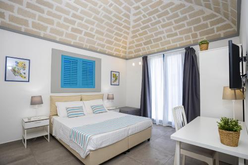 a bedroom with a bed and a desk and a tv at Acquarò Suite in San Vito lo Capo
