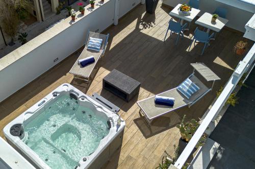 a hot tub on a balcony with a table and chairs at Acquarò Suite in San Vito lo Capo