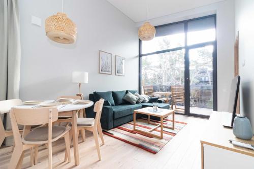 uma sala de estar com uma mesa e um sofá em Vanagupes Park Apartment, By Cohost em Palanga
