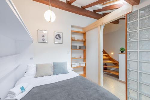 1 dormitorio con 1 cama y escalera en Ipar kale - baskeyrentals, en Mutriku