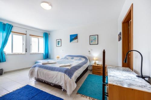 a bedroom with a large bed and blue rugs at Casa Da Paz in Salema