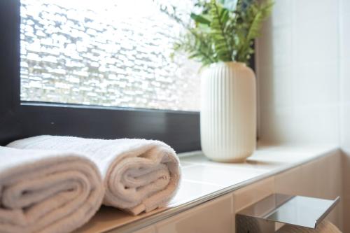 ein Badezimmer mit Handtüchern auf einer Fensterbank mit einer Vase in der Unterkunft Zentrales 7Seas Apartment Kaiserslautern - Balkon l 4 Pers l Self Check-in in Kaiserslautern