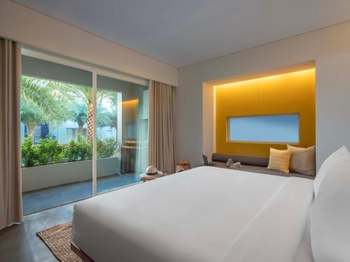 a bedroom with a large white bed and a large window at Chesa Canggu in Canggu