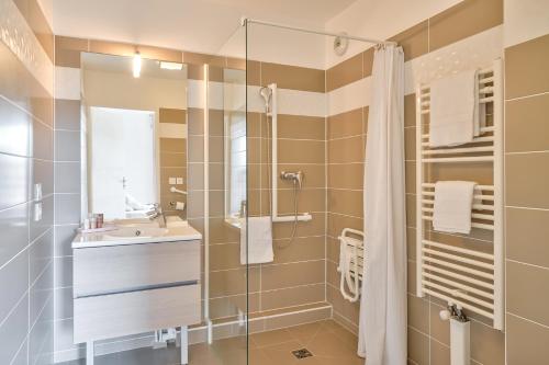 La salle de bains est pourvue d'un lavabo et d'une douche. dans l'établissement OVELIA Chatou - Le Carré Brimont, à Chatou