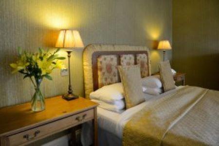 a bedroom with a bed and a table with two lamps at Mabie House Hotel in Dumfries
