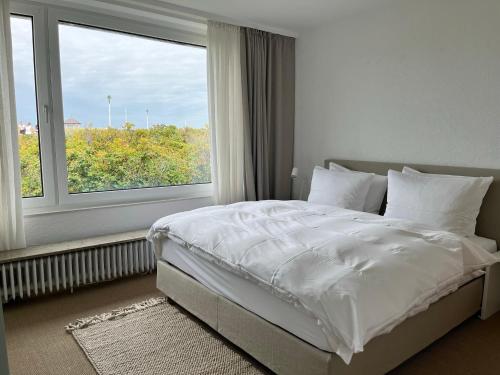 een slaapkamer met een wit bed en een groot raam bij Haus Janus 3 - Wohnung 2 in Norderney