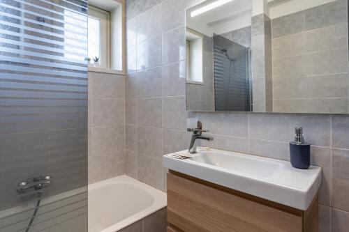 uma casa de banho com um lavatório, um espelho e uma banheira em Lovely Flat with Balcony and Private Parking em Aci Castello