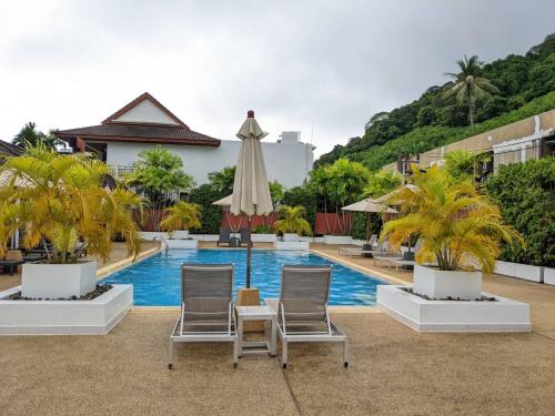 una piscina con due sedie e un ombrellone di The Sands beach apartment a Nai Harn Beach