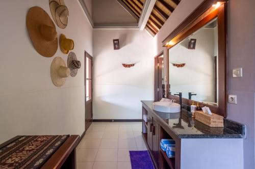 La salle de bains est pourvue d'un lavabo et d'un miroir. dans l'établissement Villa Santai Pemuteran, à Pemuteran