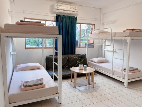 Pokój z 3 łóżkami piętrowymi i stołem w obiekcie Films House Hostel w mieście Bang Saen