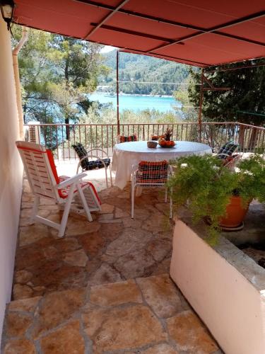 a patio with a table and chairs under an umbrella at Seafront Apartment Dana in Vela Luka