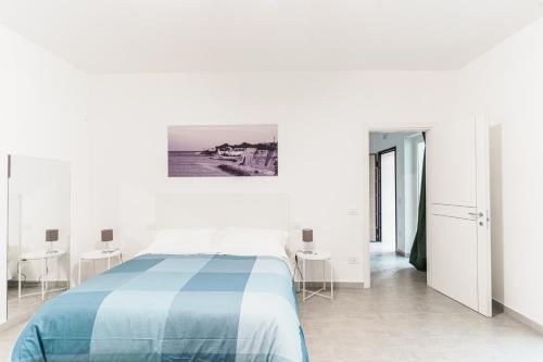 a white bedroom with a blue bed and tables at Le Marine Apartments in Bisceglie